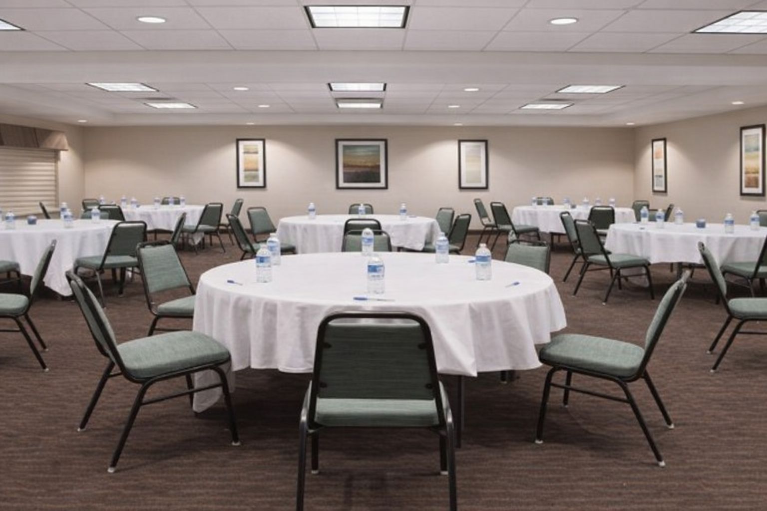 Mötesrum med runda bord och stolar, redo för en konferens.