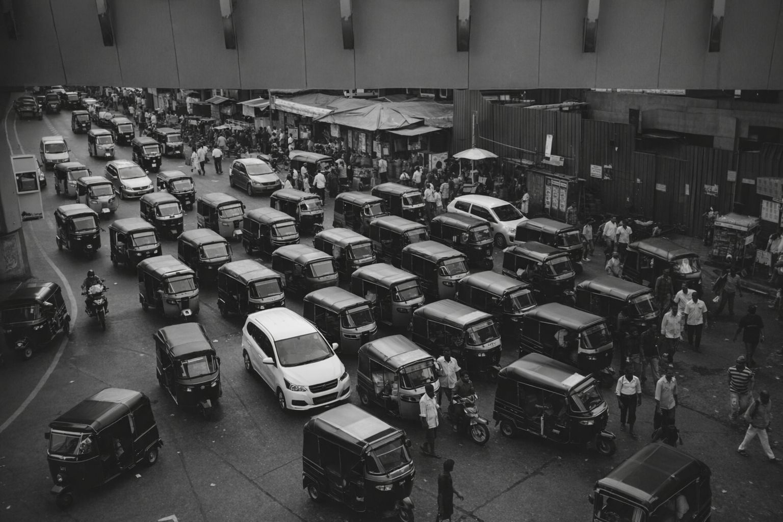 Svartvit flygbild över tät trafik med bilar och rickshaws i en stad.