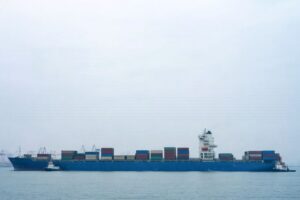 Ett stort blått containerfartyg på havet som transporterar gods.